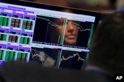 FILE- Specialist Frank Masiello is reflected in his screen on the floor of the New York Stock Exchange, Aug. 24, 2015.