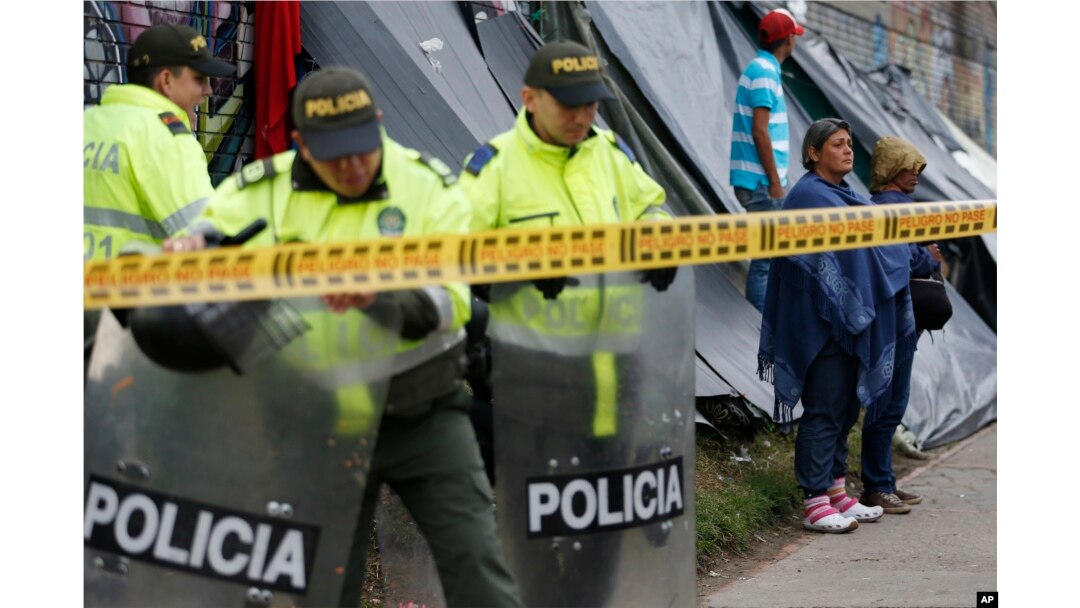 Police stand guard at a makeshift migrant settlement near the main bus terminal in Bogota, Colombia, Nov. 13, 2018.