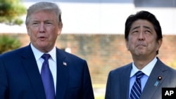 U.S. President Donald Trump, left, meets with Prime Minister Shinzo Abe upon the arrival at the Kasumigaseki Country Club in Kawagoe, near Tokyo, Nov. 5, 2017.