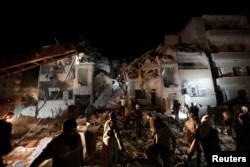 FILE - Civilians and civil defense members look for survivors at a site damaged after suspected Russian airstrikes on the Syrian rebel-held city of Idlib, Syria, late May 30, 2016.