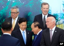 Vietnamese Prime Minister Nguyen Xuan Phuc (center right) shakes hands with Chinese Minister of Commerce Zhong Shan (center left) as Philippine Trade Secretary Ramon Lopez (top left) U.S Trade Representative Robert Lighthizer (top right) and Peruvian Trade Minister Eduardo Ferreyros (bottom right) gather for a group photo at the Asia-Pacific Economic Cooperation (APEC) Trade ministerial meeting in Hanoi, Vietnam, May 20, 2017.