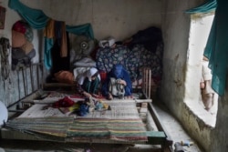 Perempuan pengungsi Afghanistan membuat karpet di rumah mereka di sebuah kamp pengungsi di Peshawar. (Foto: AFP)