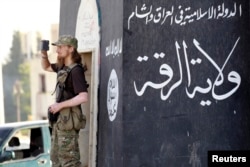 FILE - A militant Islamist fighter uses a mobile to film his fellow fighters taking part in a military parade along the streets of Syria's northern Raqqa province, June 30, 2014. .