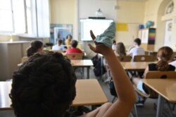 Seorang siswa mengenakan masker di tangannya saat bertanya kepada gurunya di ruang kelas sebuah sekolah dasar Carl Orff di Berlin barat, 10 Agustus 2020. (Foto: dok).