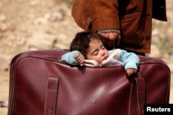Seorang anak tidur di dalam tas di desa Beit Sawa, Ghouta timur, Suriah 15 Maret 2018.