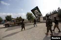 FILE - Turkish-backed Free Syrian Army fighters remove a picture of Kurdistan Workers Party (PKK) leader Abdullah Ocalan in Kafr Jana village north of Afrin, Syria, March 7, 2018.