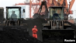 FILE - An employee walks between front-end loaders which are used to move coal imported from North Korea at Dandong port in the Chinese border city of Dandong, Liaoning province, Dec. 7, 2010.