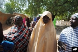 Falmata Abubakar, center, one of the kidnapped girls from the Government Girls Science and Technical College Dapchi who was freed, is photographed after her release, in Dapchi, Nigeria, March. 21, 2018.