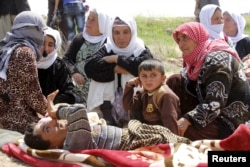 FILE - More than 200 Yazidi sect members, freed eight months after they were taken captive by Islamic State militants, wait on the edge of Kirkuk for relocation, April 8, 2015.