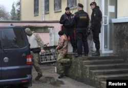 A crew member, center, of one of three Ukrainian naval ships attacked and seized Sunday by Russia is escorted after a court hearing in Simferopol, in Russia-annexed Crimea, Nov. 27, 2018.