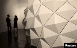 Visitors stand around the showcase piece by Iranian sculptor Sahand Hesamiyan at the Third Line Gallery in Dubai, Nov. 19, 2014.