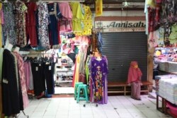 Seorang penjual baju menunggu pelanggan di pasar yang sepi, di Jakarta, 10 April 2020. (Foto: AP)