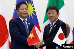 Vietnam's Industry and Trade Minister Tran Tuan Anh, left, and Japan's Minister of Economic Revitalization Toshimitsu Motegi shake hands after a news conference on the Trans Pacific Partnership (TPP) Ministerial Meeting during APEC 2017 in Danang, Vietnam