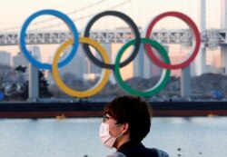 Seorang pria mengenakan masker di tengah pandemi COVID-19 di depan arena Cincin Olimpiade raksasa di Tokyo, Jepang, 13 Januari 2021. (REUTERS / Kim Kyung-Hoon)