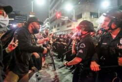 n this May 29, 2020, photo, protesters confront police officers during a protest over the death of George Floyd in Los Angeles.