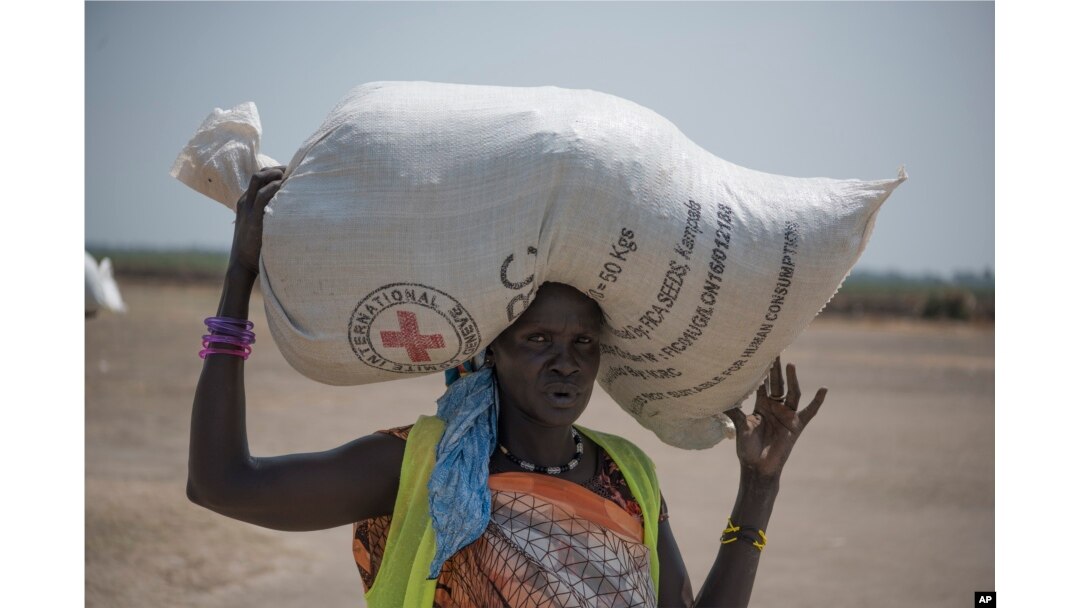 FILE - In this photo taken April 11, 2017, a woman walks back to her home after receiving food distributed by the Red Cross in South Sudan.