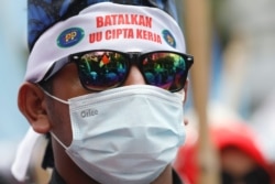 Seorang anggota serikat buruh mengenakan ikat kepala bertuliskan "batalkan UU Cipta Kerja" dalam demo memprotes perubahan aturan ketenagakerjaan, Senin, 25 November 2021. (Foto: Reuters)