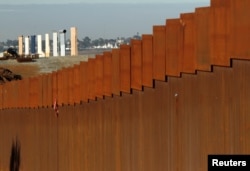 FILE - Prototypes for U.S. President Donald Trump's border wall are seen behind the border fence between Mexico and the United States, in Tijuana, Mexico, Jan. 7, 2019.