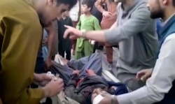 Orang-orang merawat seorang pria yang terluka di dekat lokasi ledakan mematikan di luar bandara di Kabul, Afghanistan, Kamis, 26 Agustus 2021. (Foto: AP)