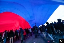 People hold a huge Russian flag during a rally to celebrate the second anniversary of Russia's annexation of Crimea just off Red Square in Moscow, Russia, March 18, 2016.