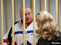 FILE - Sergei Skripal, a former colonel of Russia's GRU military intelligence service, talks to an unidentified woman from inside a defendant's cage as he attends a hearing at the Moscow military district court, Russia, Aug. 9, 2006. Skripal ended up in Briatin as part of a spy swap.