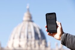 Seorang pria menunjukkan aplikasi 'Click to Pray', aplikasi smartphone yang dirancang untuk memungkinkan umat berdoa dengan sekali klik, di dekat Lapangan Santo Petrus di Vatikan, 19 Oktober 2021. (REUTERS/Guglielmo Mangiapane)