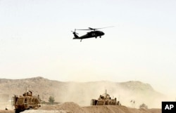 FILE - A U.S. military helicopter flies over the site of a suicide bomb attack on a NATO convoy in Kandahar, south of Kabul, Afghanistan, Aug. 2, 2017.