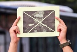 Seorang aktivis mengangkat potret Panglima Tertinggi Myanmar Jenderal Min Aung Hlaing dalam aksi menentang kudeta militer di Jakarta, Sabtu, 24 April 2021. (Foto: AP)