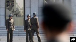 FILE - Three North Korean soldiers talk each others as a South Korean soldier watches, at the border village of Panmunjom in the Demilitarized Zone between North and South Korea, April 18, 2018.