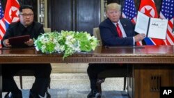 U.S. President Donald Trump holds up the document that he and North Korea leader Kim Jong Un had signed at the Capella resort on Sentosa Island, June 12, 2018, in Singapore.