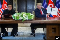 U.S. President Donald Trump holds up the document that he and North Korea leader Kim Jong Un had signed at the Capella resort on Sentosa Island, June 12, 2018, in Singapore.