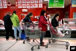 Customers shop for pork at a supermarket in Beijing, March 23, 2018.