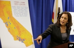 FILE - In this Mar. 24, 2016, file photo, California Attorney General Kamala Harris points to a display showing the location of Corinthian Colleges located in California during a news conference in San Francisco.