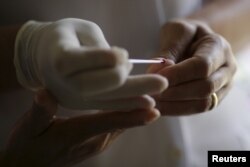 FILE - A nurse prepares an emergency test to diagnose dengue at a medical care unit of Dengue in the Sao Sebastiao neighborhood of Brasilia, Brazil, Feb. 19, 2016.