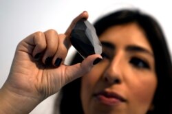 Seorang karyawan Sotheby's Dubai memperlihatkan Berlian Hitam "The Enigma" 555,55 Karat untuk dilelang di galeri Sotheby's Dubai, Uni Emirat Arab, Senin, 17 Januari 2022. (AP/Kamran Jebreili)