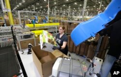 FILE - in this Feb. 13, 2015 file photo, a worker places an item in a box for shipment,at a Amazon.com fulfillment center in DuPont, Washington.