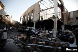 People stand at the site of an airstrike on a hall where a wake for the father of Jalal al-Ruweishan, interior minister in the Houthi-dominated Yemeni government, was being held, in Sana'a, Yemen, Oct. 8, 2016.