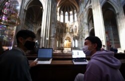 Mahasiswa Universitas Wina yang memakai masker wajah belajar di dalam gereja Votivkirche di tengah wabah Covid-19, di Wina, Austria, 6 Oktober 2020. (Foto: REUTERS/Lisi Niesner)