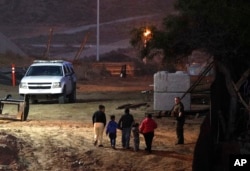 Migrants traveling with children walk up a hill to a waiting U.S. Border Patrol agent just inside San Ysidro, Calif., after climbing over the border wall from Playas de Tijuana, Mexico, Dec. 3, 2018.