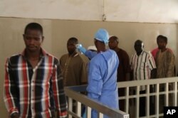 A health worker, center, takes the temperature of people to see if they might be infected by the Ebola virus inside the Ignace Deen government hospital in Conakry, Guinea, March 18, 2016.