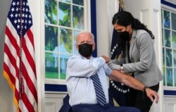 U.S. President Joe Biden holds up his sleeve to receive his coronavirus disease (COVID-19) booster vaccination in the Eisenhower Executive Office Building's South Court Auditorium at the White House in Washington, U.S., September 27, 2021
