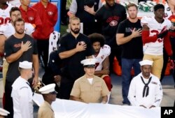 San Francisco 49ers quarterback Colin Kaepernick, middle, kneels during the national anthem before the team's NFL preseason football game against the San Diego Chargers, Thursday, Sept. 1, 2016.