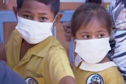 Anak-anak di Kepulauan Samoa mengenakan masker dan menunggu giliran vaksinasi di sebuah puskesmas di Apia, Samoa.