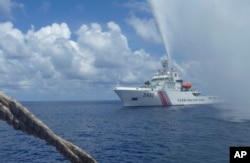 FILE - A Chinese Coast Guard boat approaches a Filipino fishing vessel off Scarborough Shoal in the South China Sea, Sept. 23, 2015.