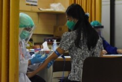 Seorang sukarelawan sedang menjalani pemeriksaan sebelum menerima suntikan calon vaksin Covid-19 dalam uji klinis di Rumah Sakit Universitas Padjajaran, di Bandung, Jawa Barat, 6 Agustus 2020. (Foto: Timur Angin/AFP)