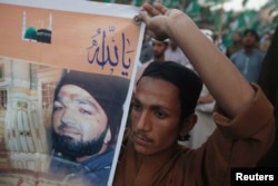 FILE - A supporter of a religious political party holds a banner of convicted killer Mumtaz Qadri during a demonstration against Qadri's sentence, in Karachi, Pakistan, March 9, 2015.