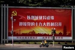 A man rides an electric scooter past a poster, promoting the 19th National Congress of the Communist Party of China