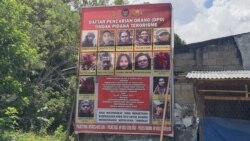 Baliho Daftar Pencarian Orang (DPO) Polisi yang memuat nama dan foto anggota kelompok Mujahidin Indonesia Timur (MIT) yang terpajang di Desa Tongoa, Kecamatan Palolo, Kabupaten Sigi, Sulawesi Tengah, Sabtu, 12 Desember 2020. (Foto: Yoanes Litha/VOA)