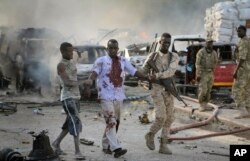 A Somali soldier helps a civilian who was wounded in a blast in the capital of Mogadishu, Somalia, Oct. 14, 2017.