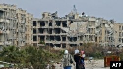 FILE - Residents of a suburban neighborhood on the edge of the northern Syrian city of Aleppo, facing Kafr Hamra, return to their homes to check the damage caused by fighting between regime forces and rebel fighters, Feb. 18, 2020.